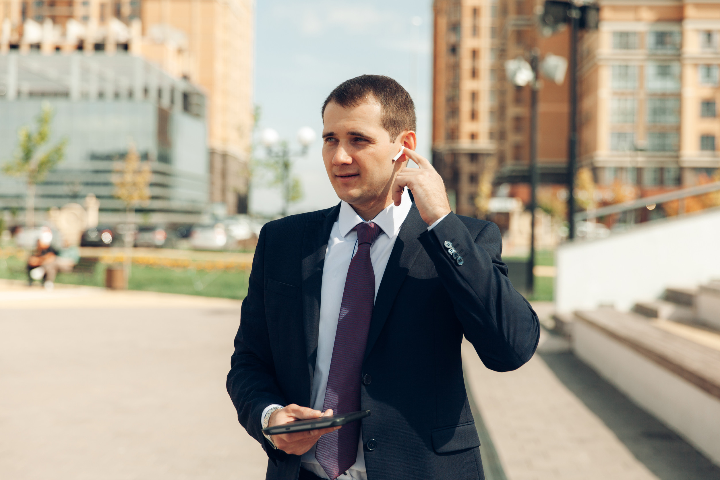 Young handsome businessman in a suit is talking in headphones and smiling. business.